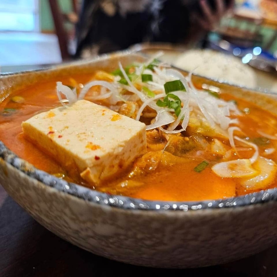 Close-up of a Japanese kimchi hot pot with tofu, green onions, and white onions.