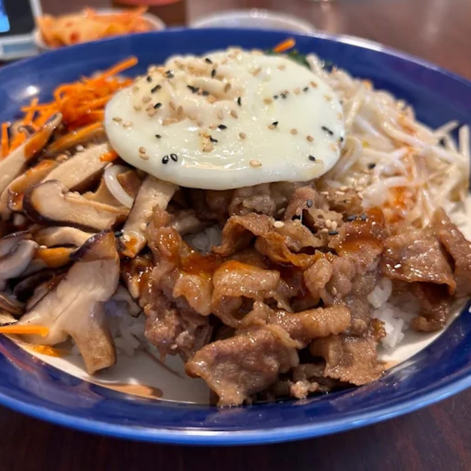 A Donburiya Cafe donburi bowl with beef, mushrooms, carrots, bean sprouts, and a fried egg.