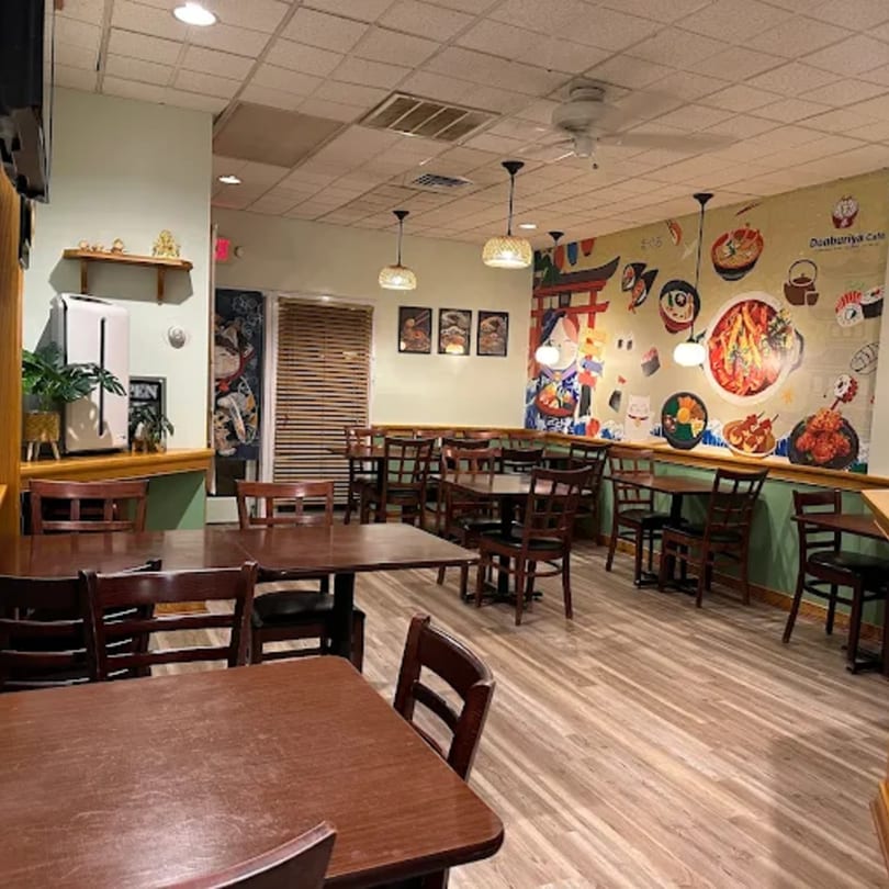 Interior of Donburiya Cafe with wooden tables and chairs, and a colorful Japanese-themed mural.