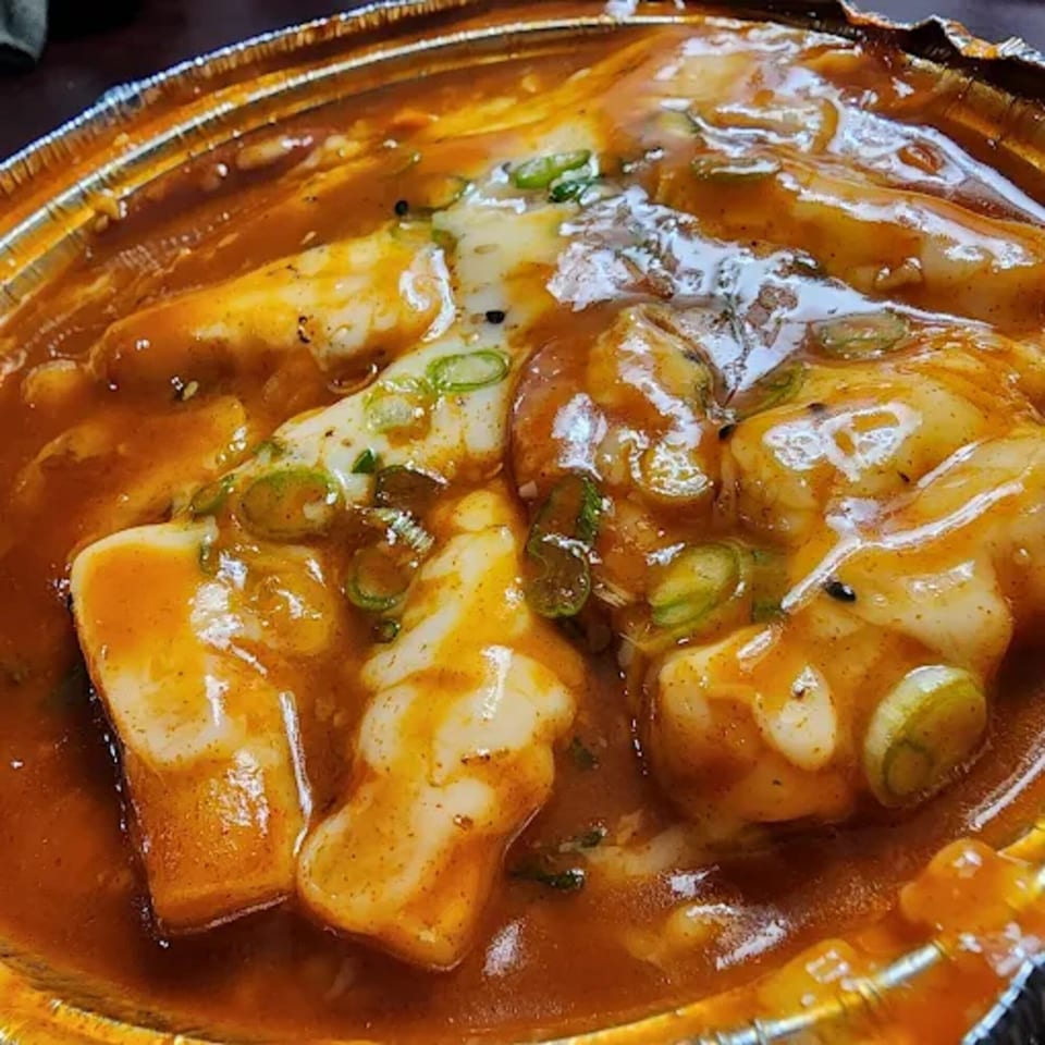 Close-up of Donburiya Cafe's Japanese dish with rice cakes, melted cheese, and green onions in a rich sauce.