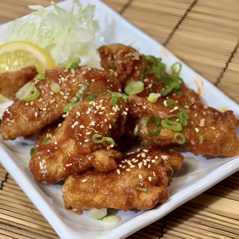 Crispy Donburiya Cafe chicken wings glazed with sauce, sesame seeds, and green onions, with lemon and lettuce.
